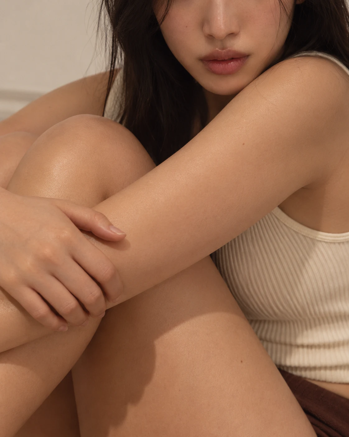 팔과 무릎을 감싸 안고 앉아 있는 여성